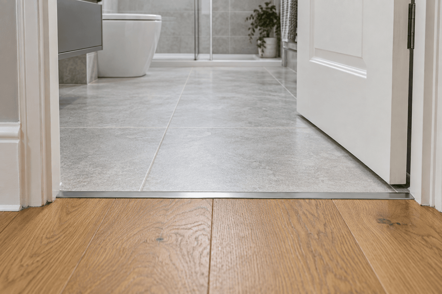 Illustration of a bathroom tile threshold meeting an oak floor beneath a door with clearance.