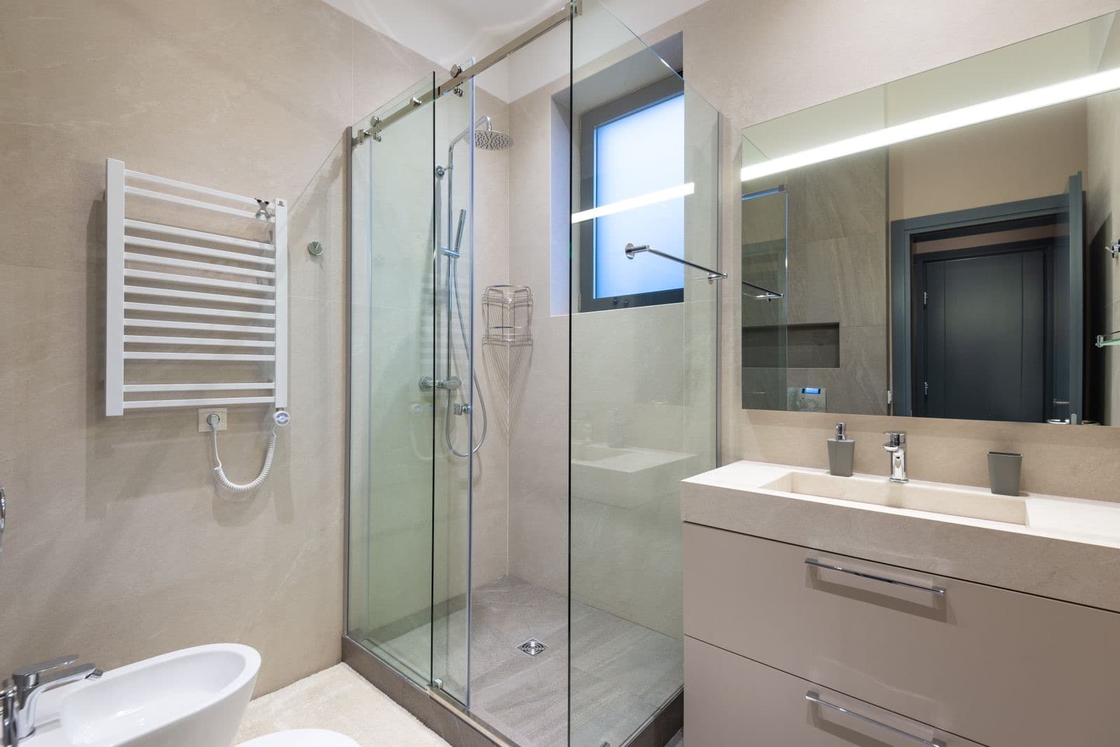 stock photograph of a walk-in shower enclosure, window, vanity basin and heated towel rail in a fitted bathroom. Licensed stock picture, not a photograph of Fylde Bathrooms, its staff, its premises or a job it carried out.